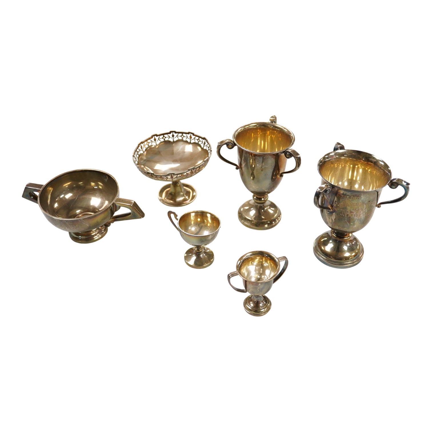 Five assorted George V silver trophy cups including two tri-handled, approx. 12.2cm and a silver bon-bon dish, with pierced border, 19.3oz.